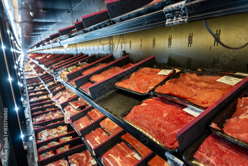 Interior view of a commercial refrigerator case in a supermarket, displaying a variety of packaged red meat cuts and poultry.