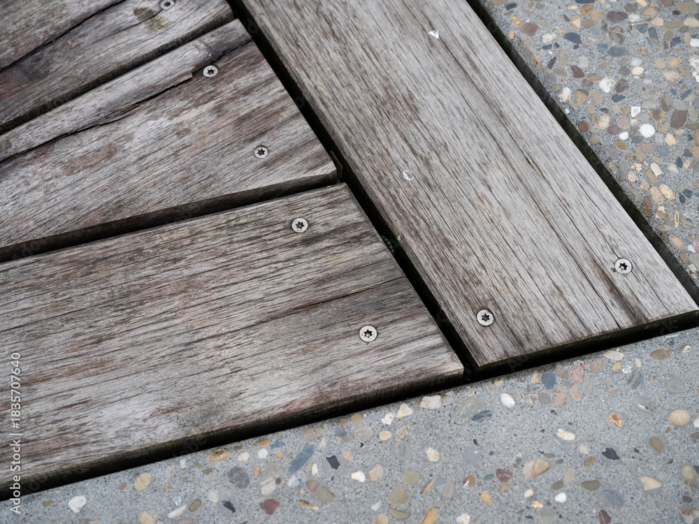 Fototapeta premium Diagonal view of weathered wooden planks with screws on terrazzo flooring showing texture contrast.