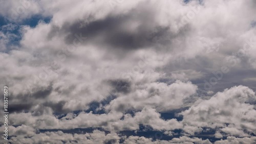 Dense layers of white and grey clouds move steadily and transform the sky from partly blue to overcast. The changing weather conditions convey a moody atmosphere.