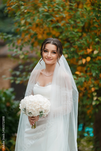 Beautiful bride holding bouquet in a serene garden during autumn
