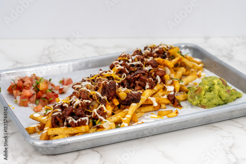 Latino food for a hungry patron includes a huge plate of asade fries loaded with cheese and sour cream