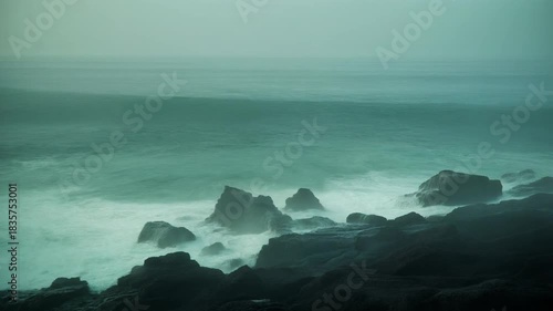 Long Exposure of Ocean Waves Crashing Against Black Volcanic Rocks at Twilight