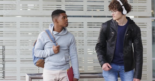 Diverse male commuters shifting gaze and listening to music on platform following newcomer entry