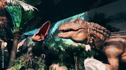 Lifelike animatronic dinosaurs moving in a jungle-themed attraction