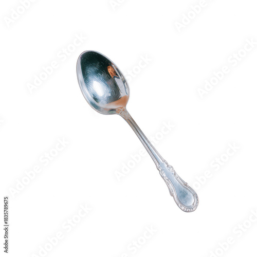 Elegant silver spoon with ornate handle reflecting warm light and subtle shadow, vintage tableware evokes cozy dining and classic kitchen charm