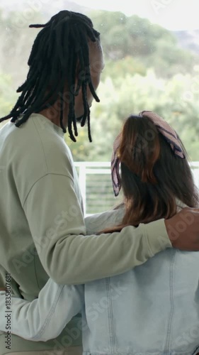 Vertical video: Putting arm round partner, taller partner on balcony glass in denim, watching trees