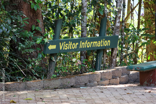 Visitor Information sign amongst trees next to a paved path