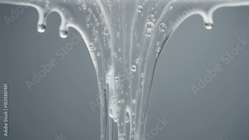 Viscous clear liquid gel slowly dripping with trapped air bubbles