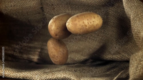 Fresh potatoes fall on the table. Filmed on a high-speed camera at 1000 fps. High quality FullHD footage