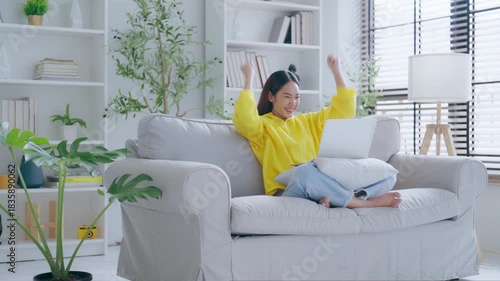 Happy euphoric young asian woman celebrating winning or getting ecommerce shopping offer on computer laptop. Excited happy girl winner looking at notebook celebrating success
