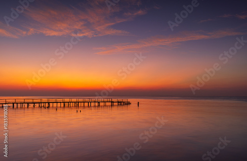 Magical and mystical sunrise on the wooden pier,View of the wooden bridge along the sea in the morning during twilight.