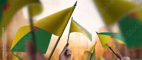 Fototapeta Naklejka Na Ścianę i Meble -  French Guiana flags in their hands on a blurred urban background