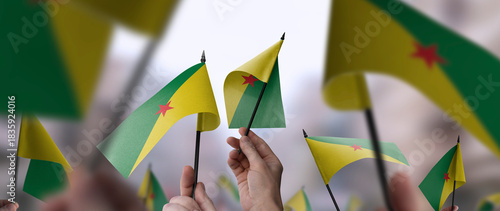 Fototapeta Naklejka Na Ścianę i Meble -  French Guiana flags in their hands on a blurred urban background