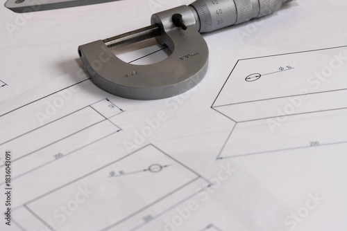 Precision micrometer placed on engineering technical drawings