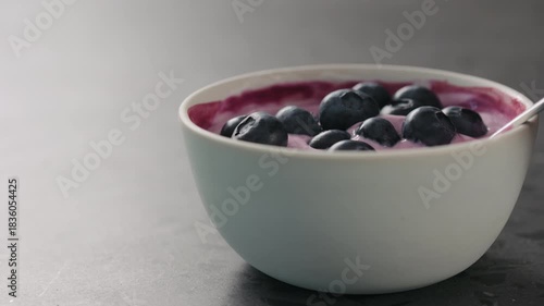 Slow motion eat yogurt with blueberries from white bowl on concrete surface