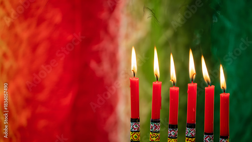 Seven red candles burning brightly on a kwanzaa kinara with a colorful background