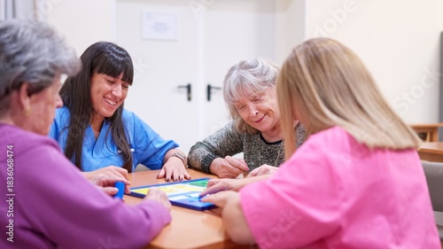 Obraz na plátně Caregivers and seniors enjoying board game together in nursing home
