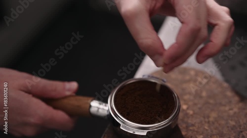 Closeup of man spreading and tamping fresh coffee in pottomless portafilter