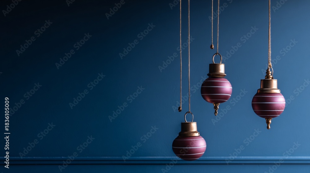 Obraz premium Three hanging ornaments with gold accents against a dark blue background.