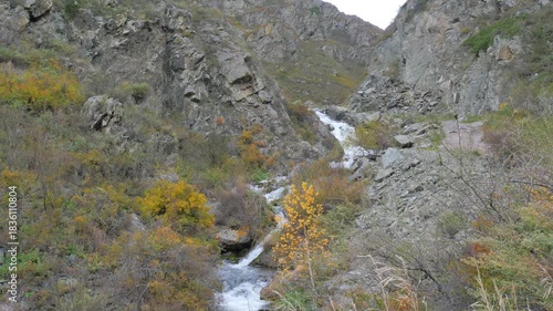 Scenic mountain gorge with a waterfall. Autumn colors enhance the rocky landscape with warm, yellow foliage.