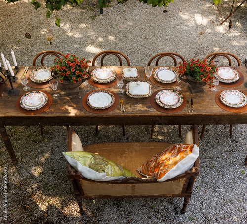 Wooden outdoor table in a garden courtyard set with vintage plates