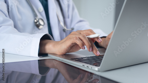 Doctor working in office, using laptop computer to access patient records on an EHR system. Medical student, female doctor using modern technology in practice for medical research, close up