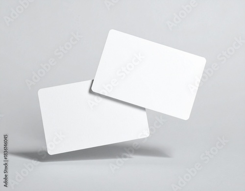 Two blank white cards floating in the air on a plain gray background, perfect for mockups