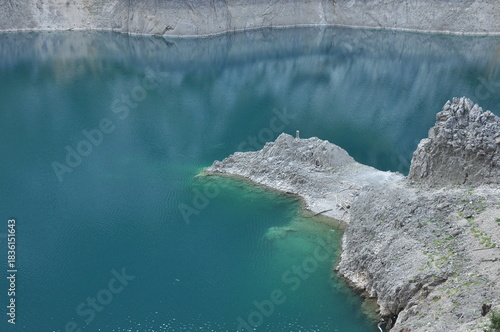Vibrant turquoise water reflecting rocky cliffs in a secluded quarry on a clear day
