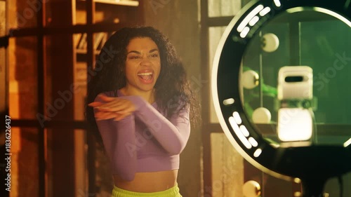Happy Black female blogger recording hip hop dance video on phone, active hobby