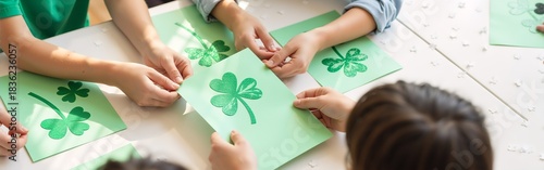 Children crafting st. patrick's day shamrocks with green paper in bright classroom