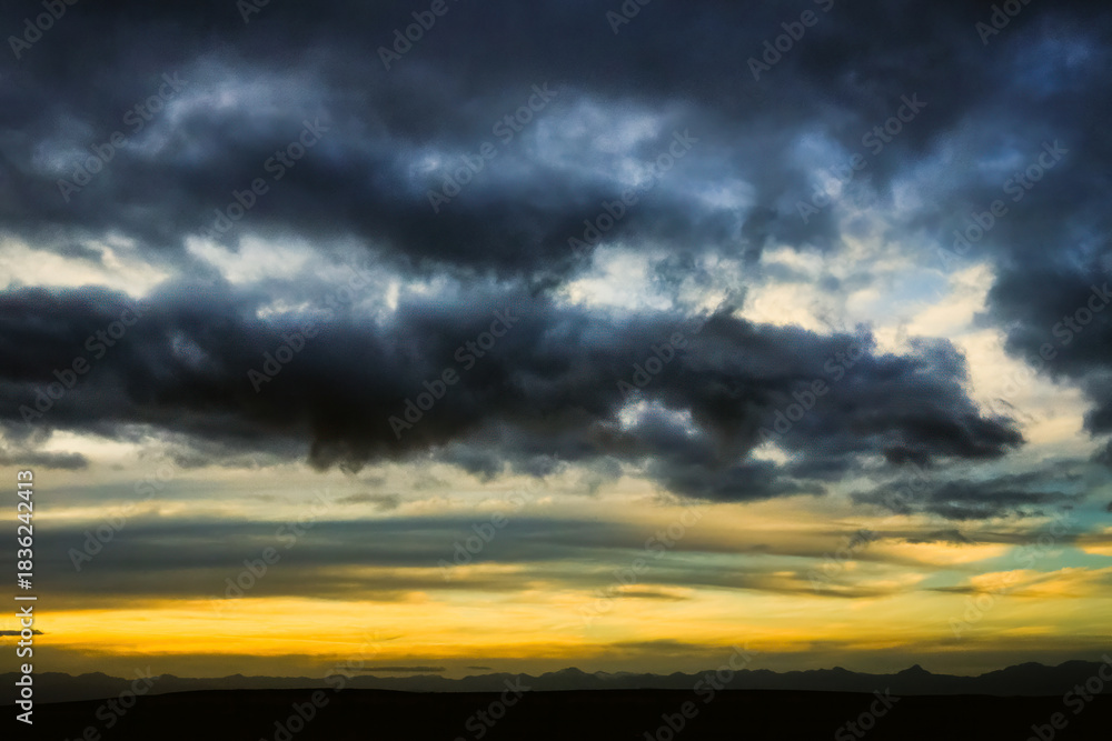 Fototapeta premium Dramatic Storm Clouds Over Vibrant Yellow Sunset Horizon