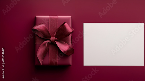 Elegante weinrote Geschenkbox mit Schleife neben leerer weißer Karte
