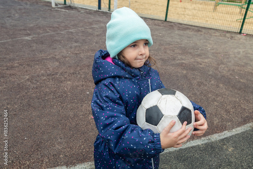 child is walking on a playground and play ball