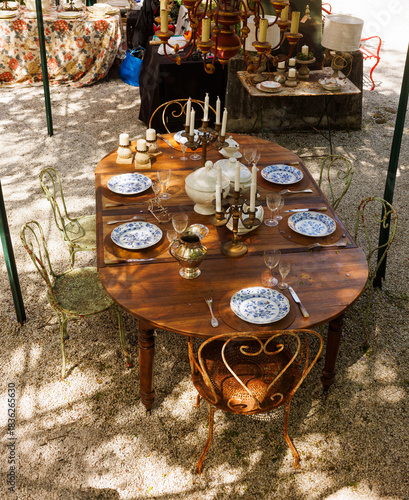 Wooden outdoor table in a garden courtyard set with vintage plates