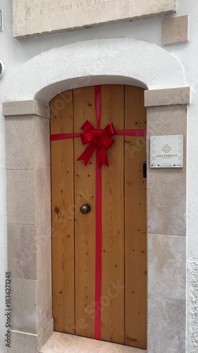 Gifted Door: A charming wooden door, adorned with a vibrant red bow and ribbon, symbolizes an invitation, wrapped in the spirit of occasion.