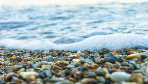 Fototapeta Naklejka Na Ścianę i Meble -  Sea wave rolling over colorful pebbles on the shore