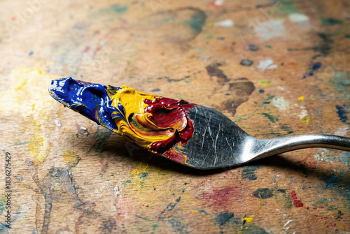 Palette Knife's Symphony: A palette knife, adorned with a vibrant array of paint strokes, rests upon a painter's workspace, depicting the very essence of artistic creation and potential.
