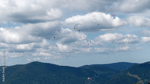 Paragliders Flying Over Mountain Landscape Under Cloudy Sky