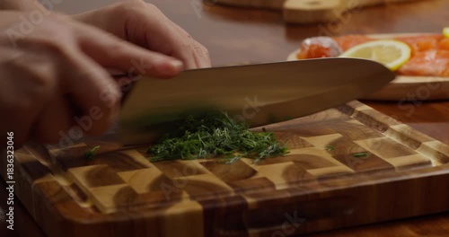 woman hands chopping fresh dill on a wooden cutting board close-up