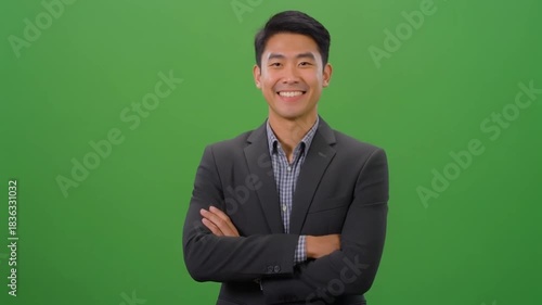 Asian businessman smiling with arms crossed on green background