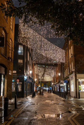 Walking on streets of Central London in Covent Garden decorated with Christmas lighting and green Christmas trees with garlands, December holidays in England