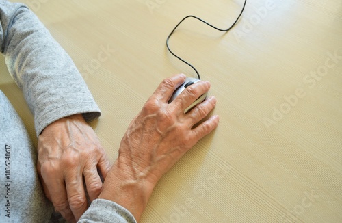 An elderly woman uses a wired computer mouse