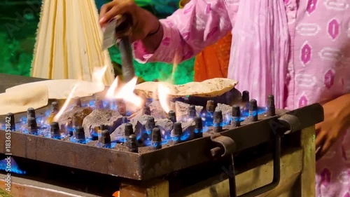 Indian roti bread being made by a lady on a open burner with stones placed to retain warmth showing how this traditional flat bread is made across north India