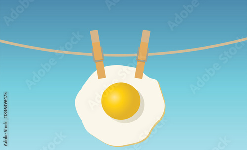 A surreal breakfast: a fried egg hanging on a clothesline with clothespins under a blue sky