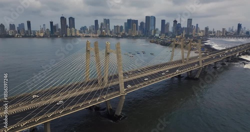 Cinematic aerial view of the Bandra Worli Sea Link in Mumbai, Maharashtra, India, during the monsoon season, with dramatic clouds and top shots of moving cars, captured from above the clouds.