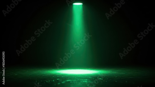 Green spotlight illuminates dark empty stage floor with atmospheric smoke.