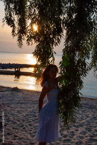 Romantic woman at sunset sea beach in summer. Woman at sea sunrise. Sunset beach sky with seascape. Summer sea beach sunrise. Girl at romantic sunset horizon. Silhouette girl sunrise. Sunset curtain