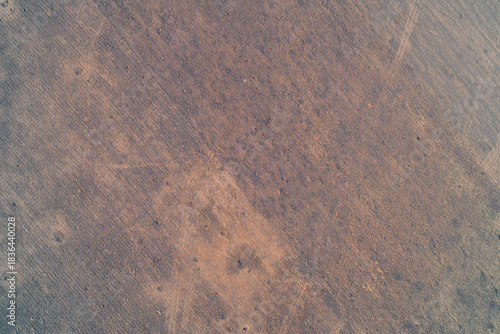 Abstract aerial view of a plowed agricultural field with subtle textures and isolated traces of shell explosions.