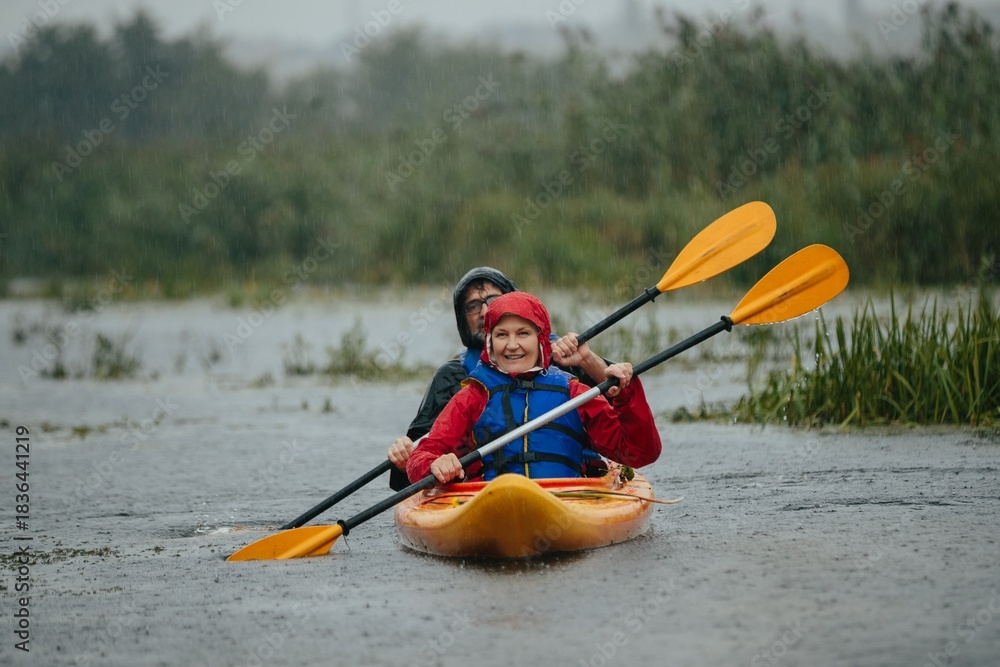 Fototapeta premium Senior couple kayaking enjoying rainy weather outdoor