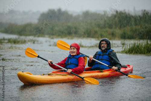 Senior couple enjoying kayaking in the rain
